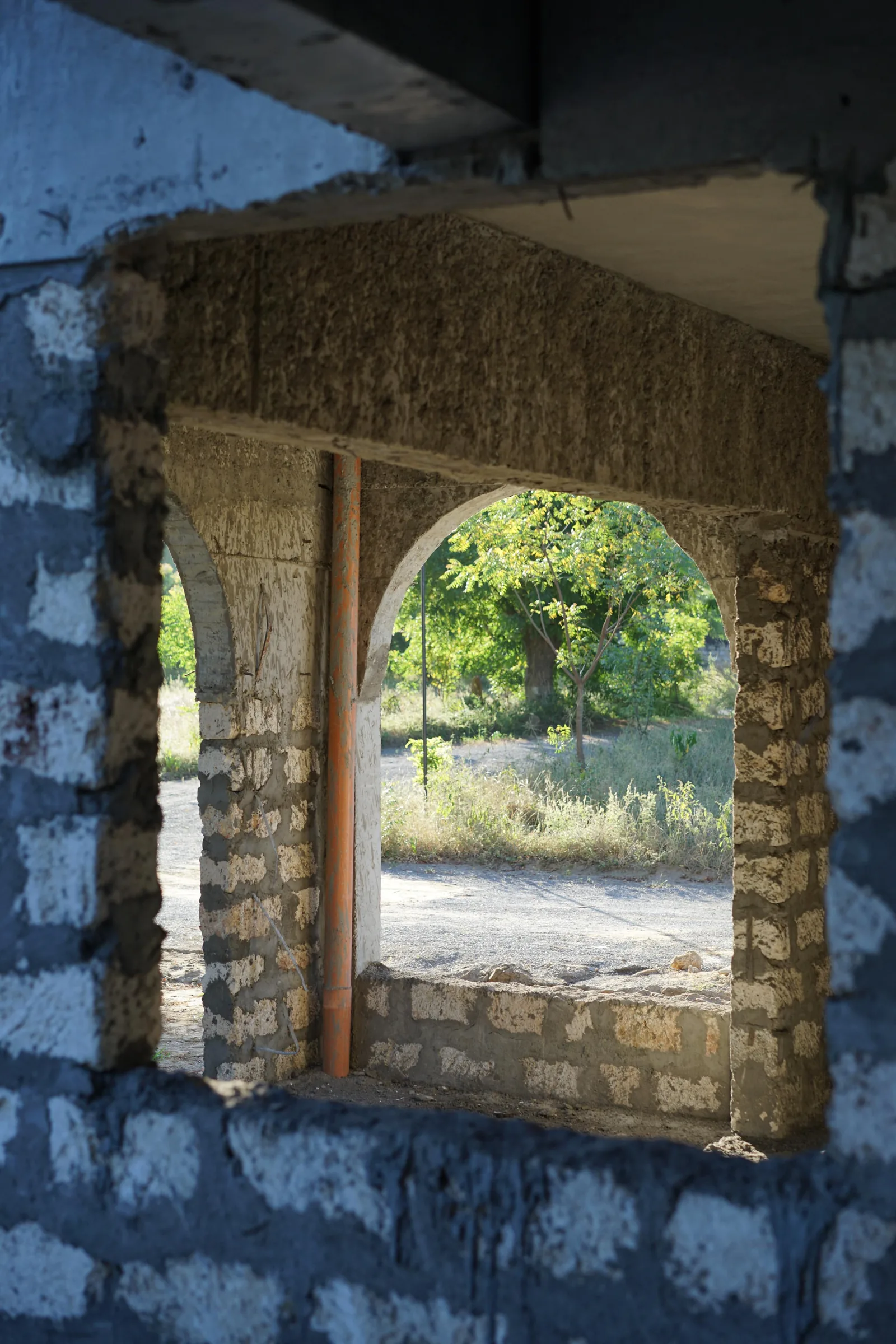 Hand-set stone-framed opening onto greenery